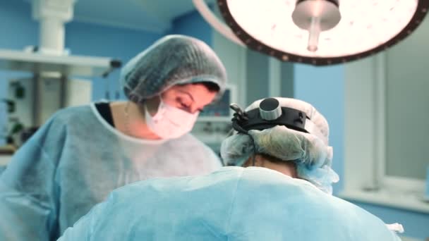 रुग्णालयाच्या आधुनिक ऑपरेटिंग रूममध्ये काम करणार्या शस्त्रक्रिया तज्ञांची वैद्यकीय टीम, शस्त्रक्रियेसाठी रुग्णाची टीम तयार करीत आहे . — स्टॉक व्हिडिओ