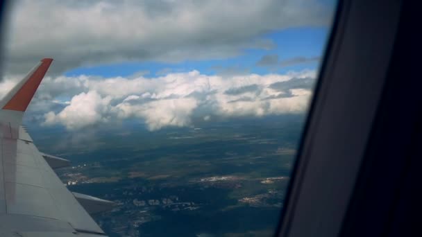 Beautiful clouds and an airplane wing out of a window with a beautiful blue sky. Shot from the porthole of an airplane while flying in high altitude with a beautiful view of the clouds and the sun. — Stock Video