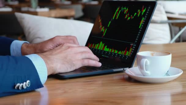 Businessman working on a laptop in a cafe, coffee break, typing on a computer keyboard, with a schedule of berge katerovki, coffee work in the city, work in large companies, trading — Stock Video