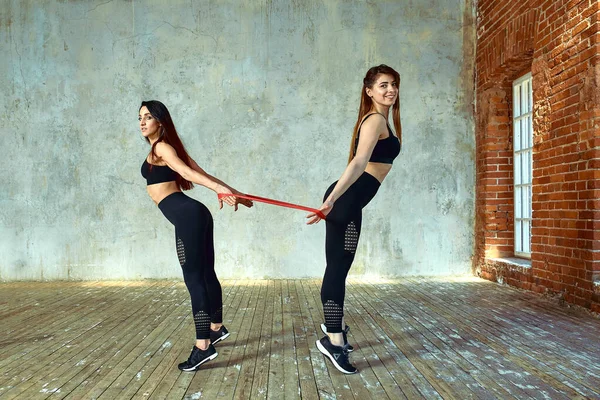 Zwei junge Frauen turnen im Fitnessraum. posieren und in die Kamera lächeln, Spaß haben, tolle Atmosphäre. — Stockfoto