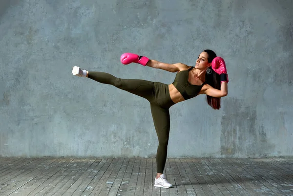Hermosa chica atlética posando en guantes de boxeo rosa sobre un fondo gris. Copiar espacio. Concepto deporte, lucha, logro de metas . — Foto de Stock