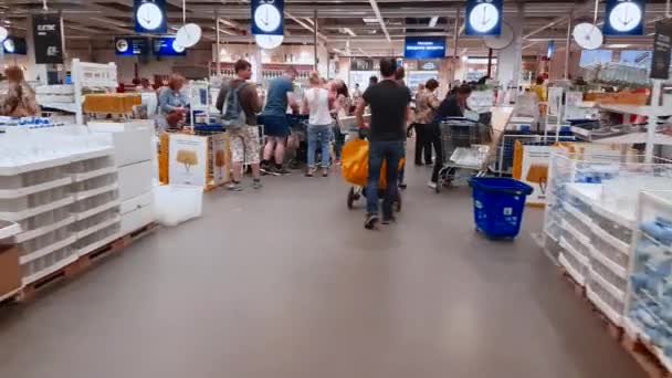Detailhandel. Shoppers met winkelwagentjes gaan in de rij staan om te betalen voor aankopen bij de supermarkt kassa. Opname van de lijnen bij de kassa in een grote supermarkt. Handheld-effect — Stockvideo