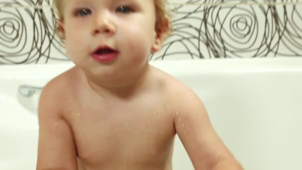 Щаслива блакитноока дитина 9-12 місяців купається у ванній кімнаті і грає з іграшками, миє та купає дітей, гігієна та догляд за маленькими дітьми — стокове відео
