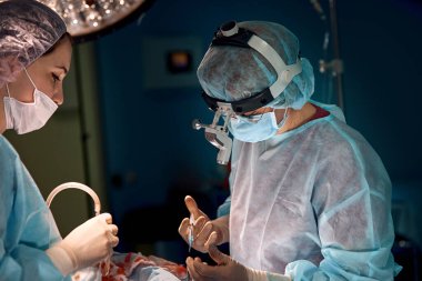 Karanlık bir ameliyathane, cerrahlar karmaşık bir antikolojik operasyon yapar. Cerrahların kadın takımı. İlaç konsepti.