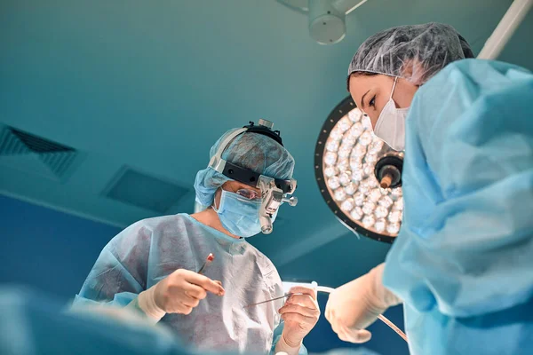 Retrato de los cirujanos en el fondo de las lámparas de funcionamiento, vista inferior. Copiar espacio, luz azul. El concepto de cirugía medecina . — Foto de Stock