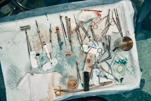 Instrumentos e instrumentos quirúrgicos, incluidos bisturíes, pinzas y pinzas, ubicados sobre la mesa para la operación, durante la operación . —  Fotos de Stock