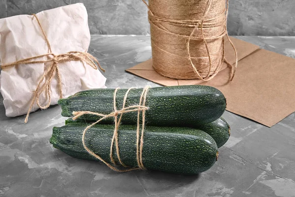 A bunch of zucchini on a gray background with a paper bag for delivery, food delivery, environmental packaging. Copy space, fresh vegetables.