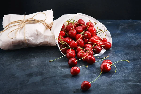 Fresh sweet cherry in a paper bag on a blue background close-up. Fresh berries concept, grocery delivery. Photo for a grocery store kologologist. — Stock Photo, Image