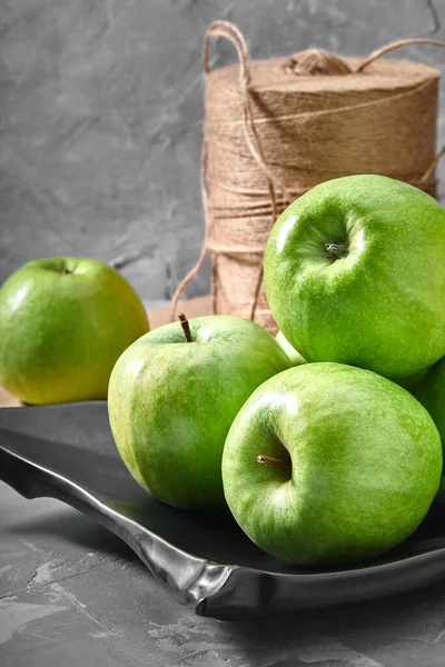 green apples lying on a gray background with a black plate ecological packaging. Delivery of products, copies of space, photos for the catalog of stores.