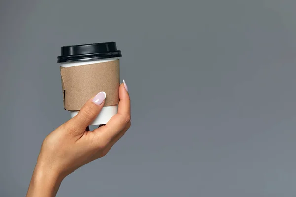 Рука девушки с бумажной чашкой кофе, серый фон Доброе утро, концепция. Пустое место для надписи . — стоковое фото