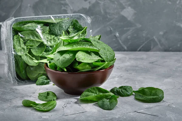 Fresh spinach in an old bowl on a gray background. Selective focus, horizontal. environmental packaging. Delivery of products, copies of space, photos for the catalog of stores. — Stock Photo, Image