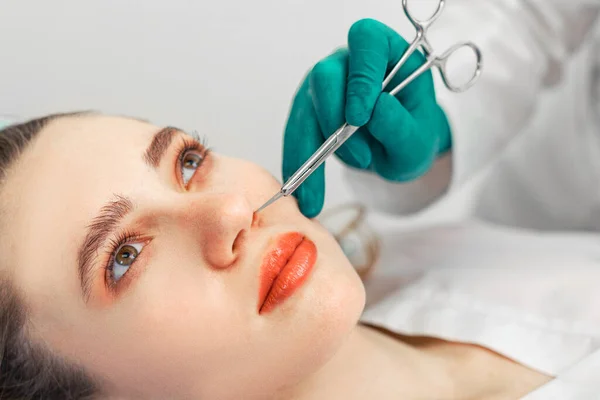 Neuscorrectie, de chirurgische handen raken de neus van de patiënt. Mensen, cosmetologie, plastische chirurgie en schoonheid concept - chirurg of cosmetoloog handen raken vrouwelijk gezicht. Kopieerruimte. — Stockfoto