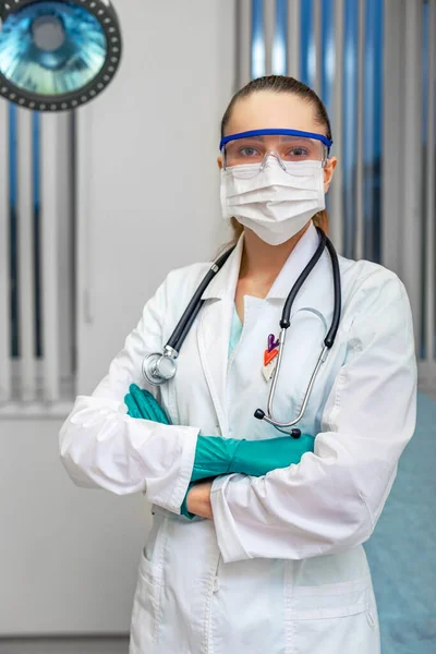 Personal protective equipment, woman doctor in personal protective equipment on the background of a hospital ward. Copy space.