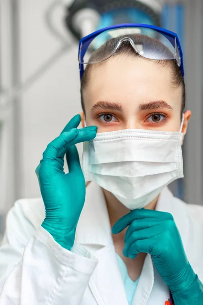 Personal protective equipment, woman doctor in personal protective equipment on the background of a hospital ward. Copy space.