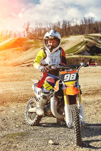 Retrato de menino vestido e equipado para corridas de moto sentado em moto . — Fotografia de Stock