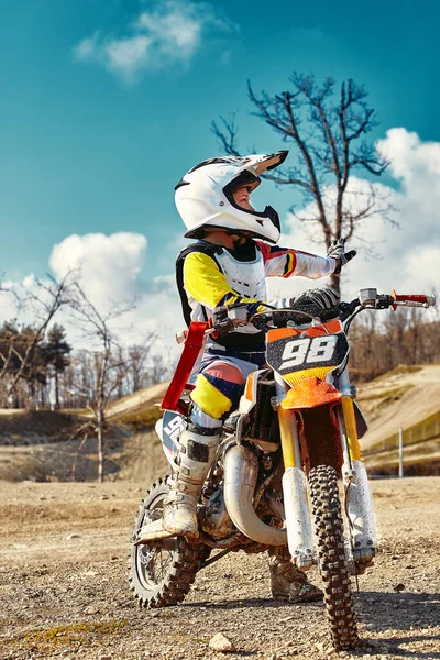 Retrato de menino vestido e equipado para corridas de moto sentado em moto . — Fotografia de Stock