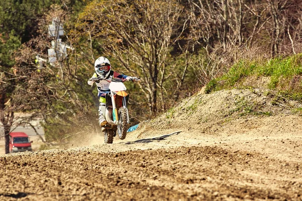 Pengendara Motocross beraksi mempercepat sepeda motor lepas landas dan melompat di springboard di lintasan balap. — Stok Foto