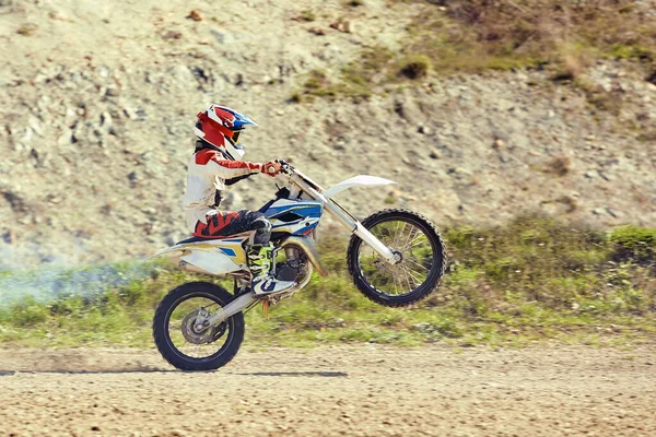 Motocross förare i aktion accelerera motorcykeln lyfter och hoppar på språngbräda på tävlingsbanan. — Stockfoto