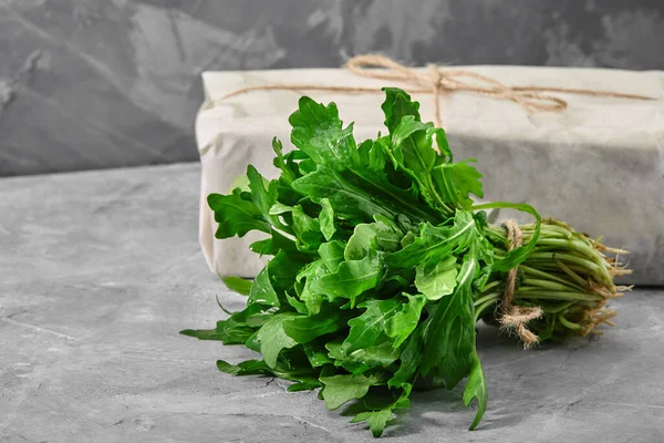 Friss rukkola levelek egy csésze konkrét háttér. Egészséges és friss saláta. Organikus és természetes ételfogalom. Fényes háttér. Lapos fektetés. — Stock Fotó