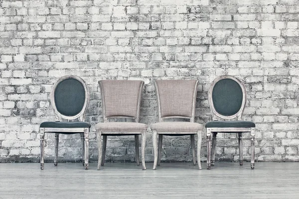 Cadeiras diferentes em uma linha contra uma parede de tijolo branco — Fotografia de Stock