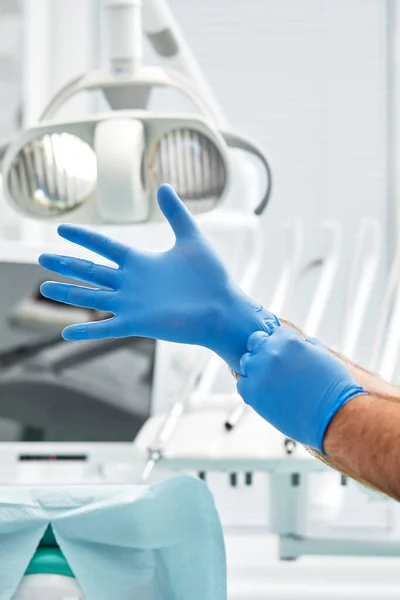 Eine Zahnärztin zieht in einer Zahnarztpraxis Handschuhe an. Glückliches Patienten- und Zahnarztkonzept. — Stockfoto