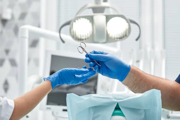 Primo piano delle mani di un dentista e di un infermiere chirurgo in una sala operatoria durante un'operazione di impianto dentale — Foto Stock