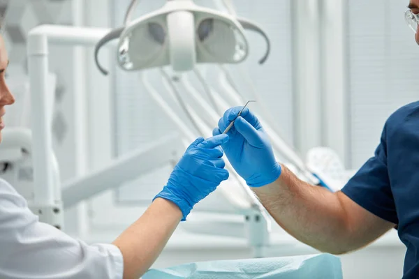 Close-up das mãos de um dentista e enfermeiro cirurgião sobre uma sala de cirurgia durante uma operação de implante dentário — Fotografia de Stock
