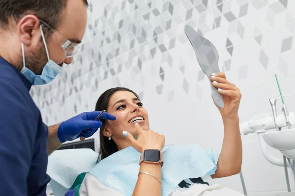 Люди, медицина, стоматология и здравоохранение концепции - счастливый мужчина стоматолог показывая план работы женщине пациента в стоматологической клинике офиса — стоковое фото