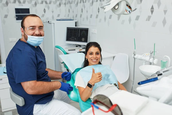 Ludzie, medycyna, stomatologia i opieka zdrowotna koncepcja - szczęśliwy męski dentysta pokazujący kobiecie plan pracy w gabinecie stomatologicznym — Zdjęcie stockowe