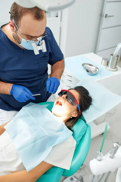 Mensen, geneeskunde, stomatologie en gezondheidszorg concept - gelukkige mannelijke tandarts met vrouw patiënt op tandheelkundige kliniek kantoor — Stockfoto