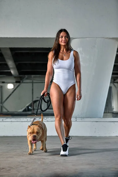 Donna con una figura atletica con cane bullo americano per le strade della città — Foto Stock