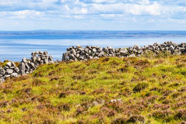Galway bay içinde geçmiş, Ballyvaughan, Clare, İrlanda ile Burren yol iz içinde taş duvar