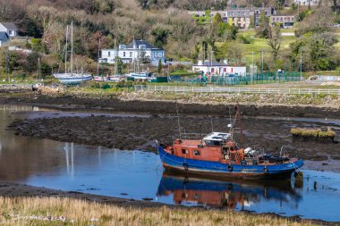 Düşük gelgit Clifden koyunda binalar ve tekne ile İskele