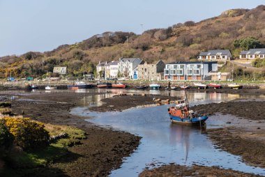Düşük gelgit Clifden koyunda binalar ve tekne ile İskele