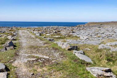 Inishmore arka planda okyanus ile kayaların etrafında Yol
