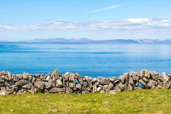 Blommade gårdsplan med bergväggar och Galway Bay i bakgrunden — Stockfoto