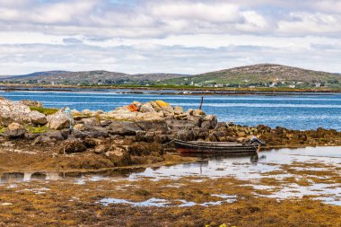 Carraroe düşük gelgit, yosun, tekne ve dağlar ile Bay