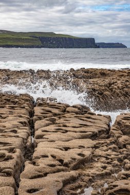 Arka planda dalgalar ve Moher Kayalıkları ile Liman plaj