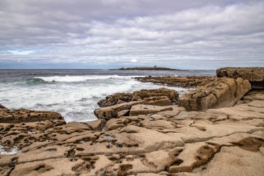 Arka planda dalgalar ve Yengeç Adası ile Liman plaj
