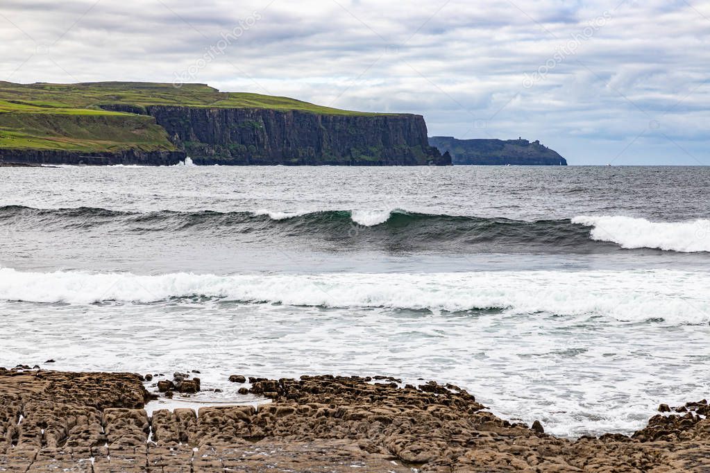 Harbour beach with waves and Cliffs of Moher in background