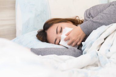 Gribi acı ve doku ile yatakta yatarken Asyalı kadın