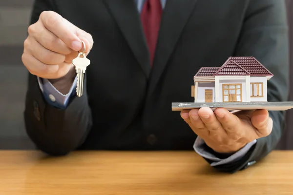 Businessman holding key and home model. Loan and real estate concept