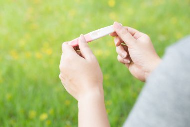 Hamilelik testi yeşil bir bahçe içinde tutan kadın