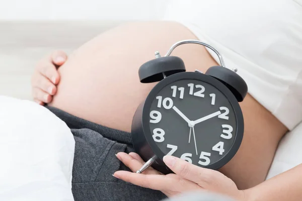 目覚まし時計で妊娠中の女性 — ストック写真