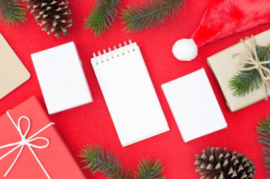 Kırmızı bir arka plan ve kopya alanı beyaz kağıt, metniniz için Noel ve mutlu yeni yıl kompozisyon, hediye kutusu, çam kozalakları, çam dalları üstten görünüm