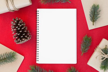 Kırmızı bir arka plan ve kopya alanı beyaz kağıt, metniniz için Noel ve mutlu yeni yıl kompozisyon, hediye kutusu, çam kozalakları, çam dalları üstten görünüm