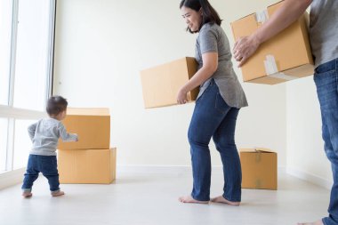 Taşındığı gün yeni evde karton kutuları olan mutlu Asyalı aile, emlak ve ev kavramı