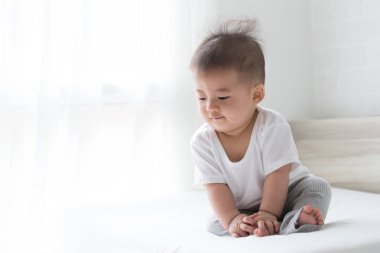 Asya bebek çocuk beyaz yatakta bir şeyler arıyorum