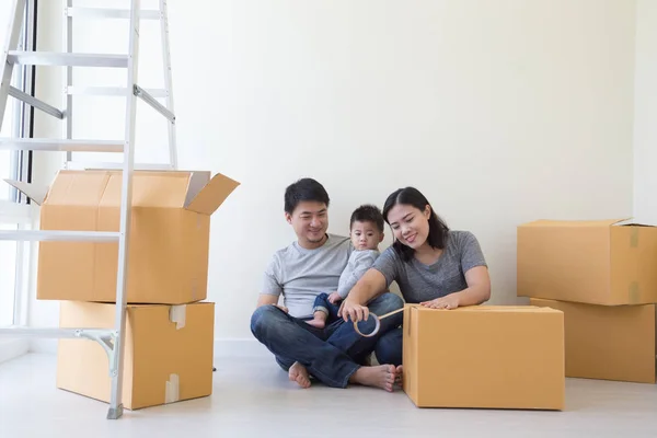 Happy Asian family with cardboard boxes in new house at moving day, Real estate and home concept