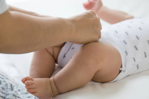 Mother changing cloth baby with bodysuit